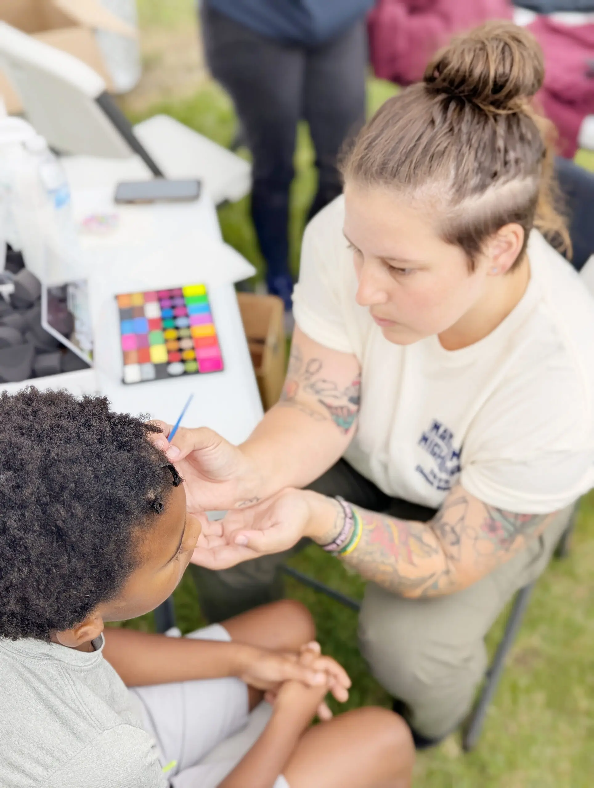 Adult painting child's face with face paint