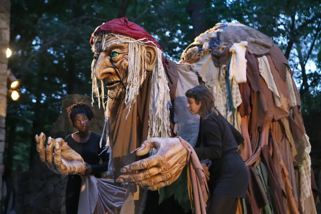Two puppeteers hold a giant puppet