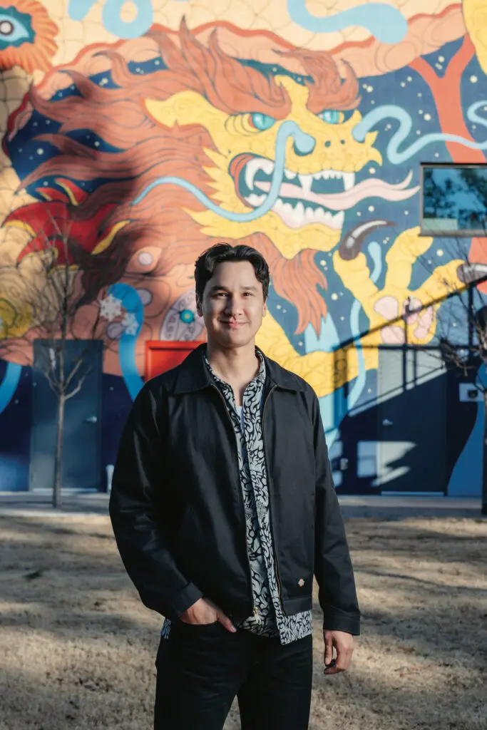 Gabriel Eng-Goetz poses in front of his mural, “Rebirth,” at Boxyard RTP in Durham