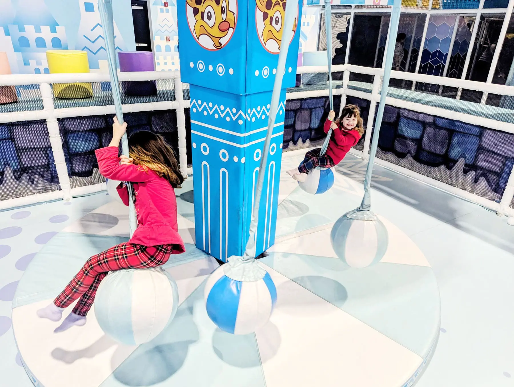 Two girls are swinging on a ride.