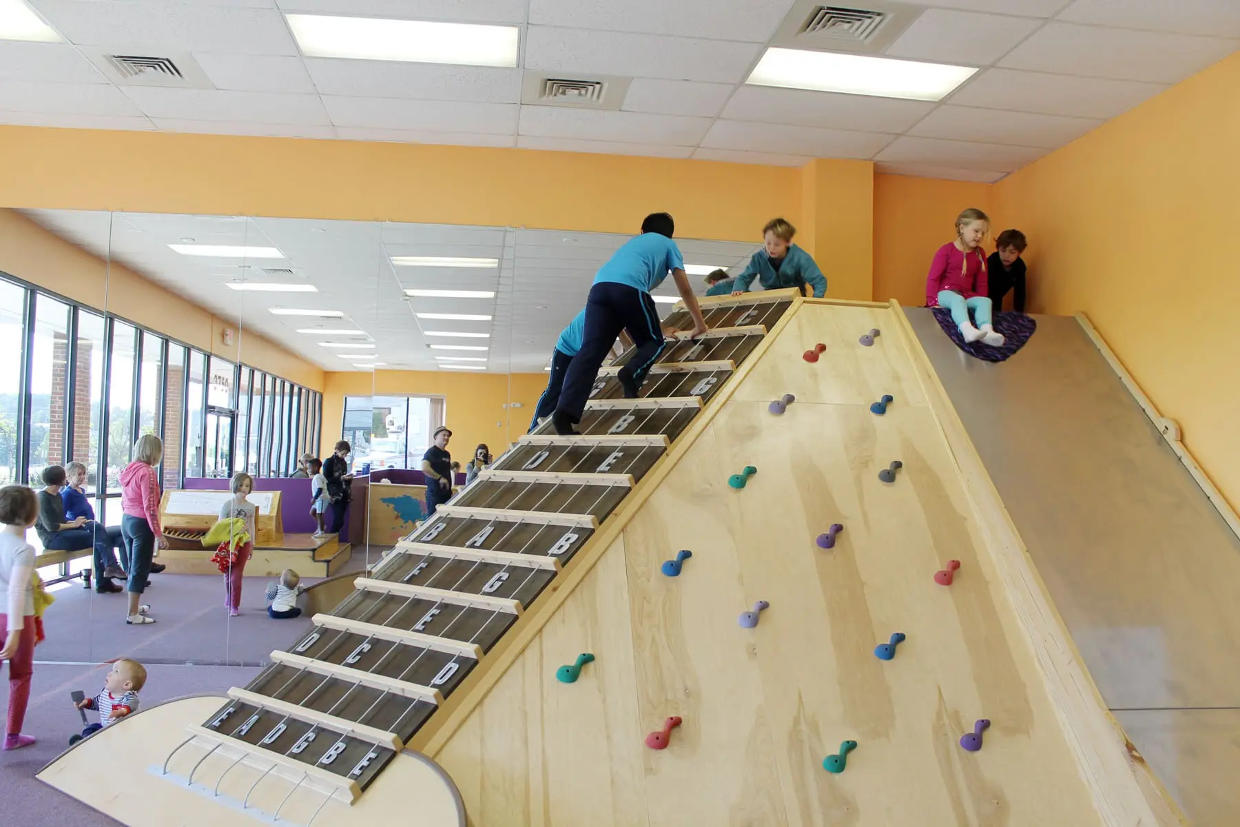 children climbing a rock-climbing wall.